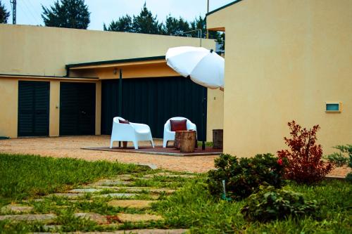 two white chairs and an umbrella in front of a building at ROTA - Opo airport house in Maia