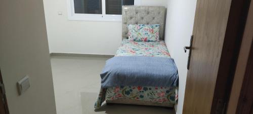 a small bed in a room next to a window at APPARTEMENT haut standing in O Ben Slimane