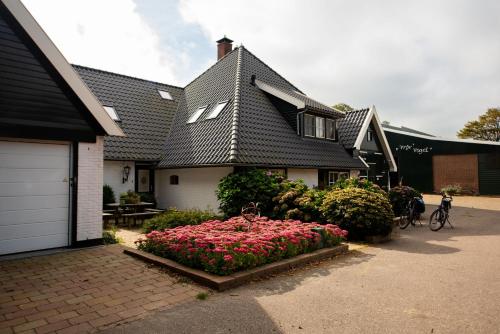 a house with a flower bed of pink flowers at Terras kamer in Spang