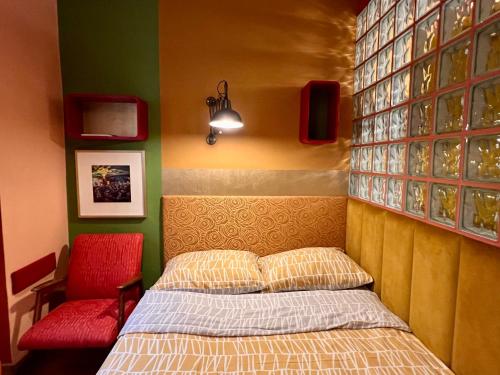 a bedroom with a bed and a red chair at MuziKafe - Home of Culture in Ptuj