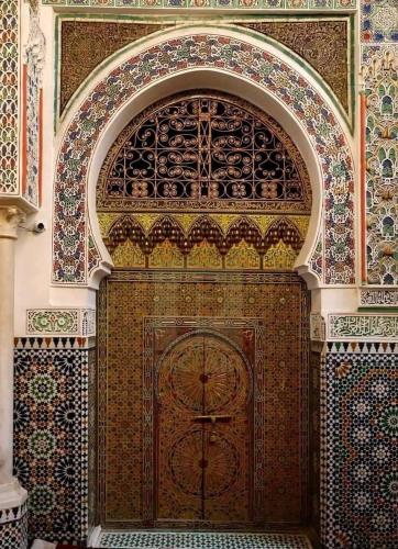 a large wooden door in a building with tiles at Riad Fès Center in Fez