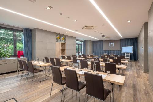 a conference room with tables and chairs and a screen at H10 Roma Città in Rome