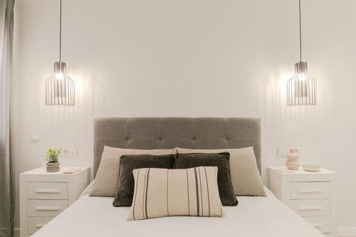 a white bedroom with a bed with two pendant lights at Avanti Murillo, Elegance & Comfort in Seville