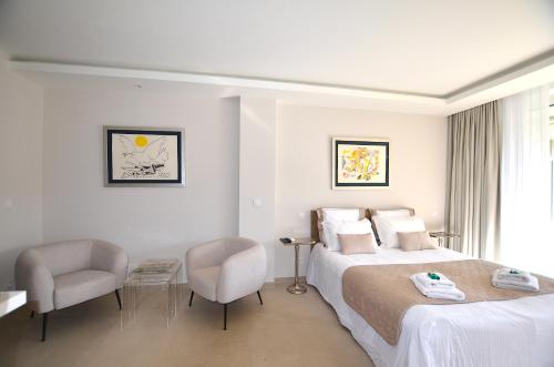 une chambre d'hôtel avec un lit et deux chaises dans l'établissement Studio Cannes Grand Hôtel Cormoran avec Terrrasse, à Cannes