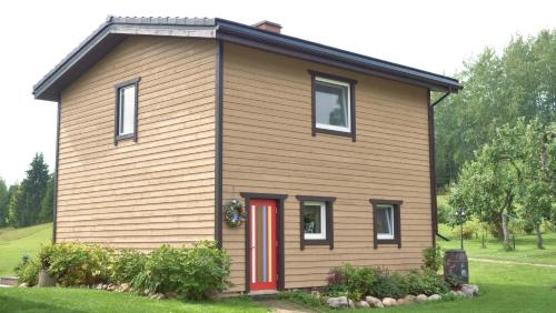 a small house with a red door on a yard at Ala Sarise saunamaja in Sarise