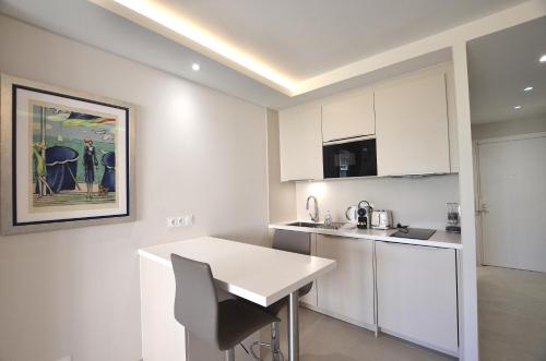 une cuisine avec des armoires blanches et une table blanche dans l'établissement Studio Cannes Grand Hôtel Cormoran avec Terrrasse, à Cannes
