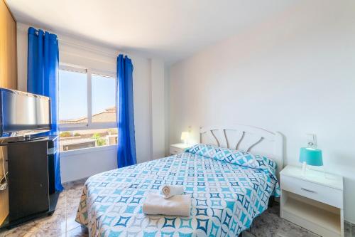 Schlafzimmer mit einem Bett mit blauen Vorhängen und einem TV in der Unterkunft Bahia Almeria in Aguadulce