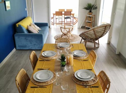 una mesa de comedor con platos y vasos. en 971B - La Villa ROUYO, villa créole accessible PMR, en Le Moule