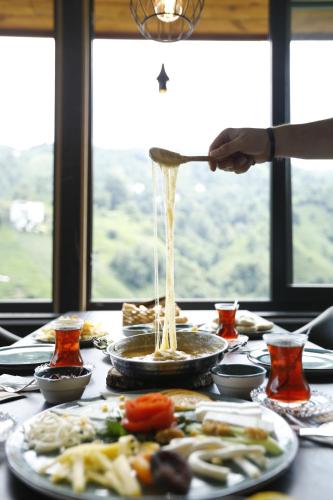 una persona está vertiendo salsa en una mesa con comida en Pafuli Bungalov, 