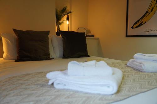 Una cama con toallas blancas encima. en Woodstock Oxford Street- Entire Cosy Apartment- 5 mins to Blenheim Palace en Woodstock