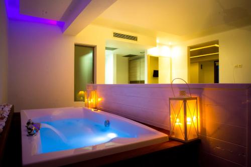 uma casa de banho com uma banheira com luzes e um espelho. em Bebis Hotel em Kókkinon Nerón