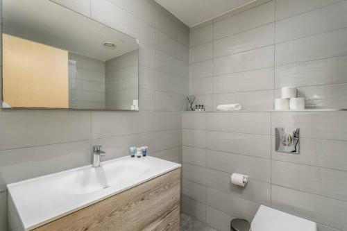 a white bathroom with a sink and a mirror at New Branch Gindi Tower 1BR with Parking in Tel Aviv