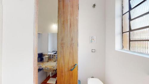 a bathroom with a wooden door in a room at Studio 8 Pinheiros by Oba in São Paulo