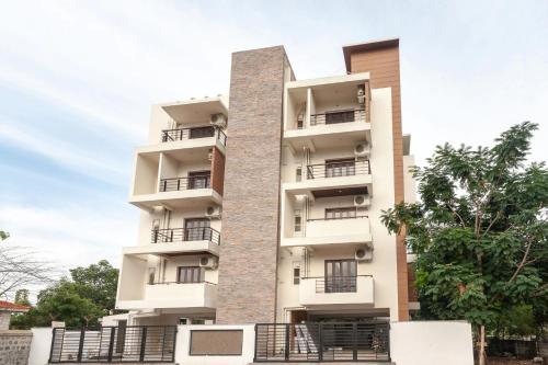 a tall white building with balconies on it at Tulips Residency - Airport in Pīlamedu