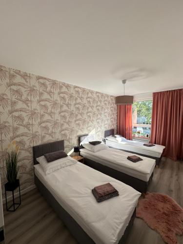 a room with three beds and a wall with wallpaper at SkyTravel 26 Apartament Pileckiego Nowy Dwór Mazowiecki Airport Modlin 24H in Nowy Dwór Mazowiecki