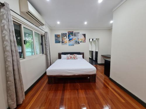 a bedroom with a bed with a wooden floor and a window at Nasese paradise in Suva