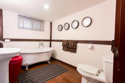 a bathroom with a tub and a toilet and a sink at Tolani Northgate Villa Chiang Mai in Chiang Mai