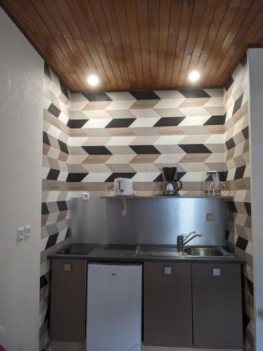 - une cuisine avec un évier et un mur en damier dans l'établissement Appartement et salle de jeu, à Saint-Claude