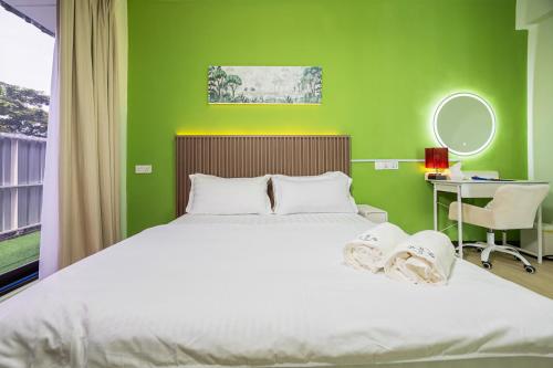 a bedroom with a white bed with a green wall at R S Home in Tawau