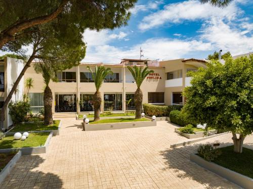 un bâtiment avec des palmiers et une cour dans l'établissement Hotel Pavlina Beach, à Niforeika