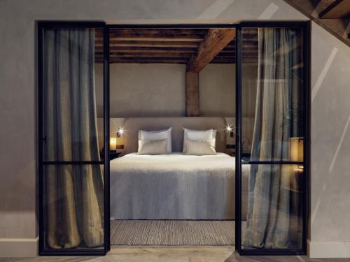 a bedroom with a white bed with a glass doorway at Botanic Sanctuary Antwerp - The Leading Hotels of the World in Antwerp