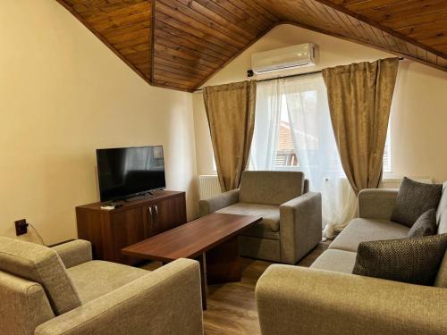 sala de estar con TV, sillas y mesa en RELAX - Guest House Varshets, en Varshets