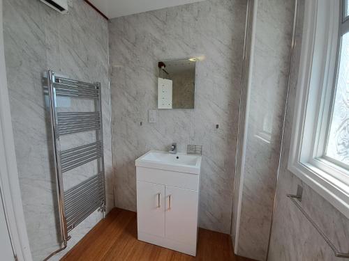 a bathroom with a white sink and a mirror at River View - Norfolk Broads in Brundall