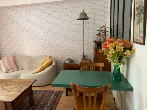 ein Wohnzimmer mit einem grünen Tisch und einer Blumenvase in der Unterkunft Maison à fleurs in Granville