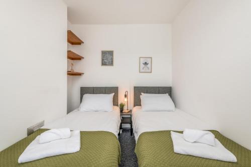 two beds in a room with white walls at Wood House by EDEN Accommodation - 3 Bedroom Whole House, Sleeps 6 in Kettering