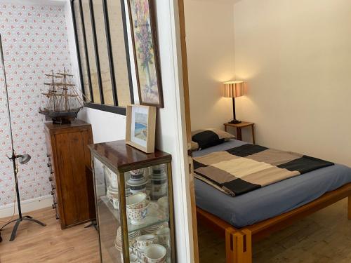 ein kleines Schlafzimmer mit einem Bett und einem Glasschrank mit einem Glas in der Unterkunft Maison à fleurs in Granville