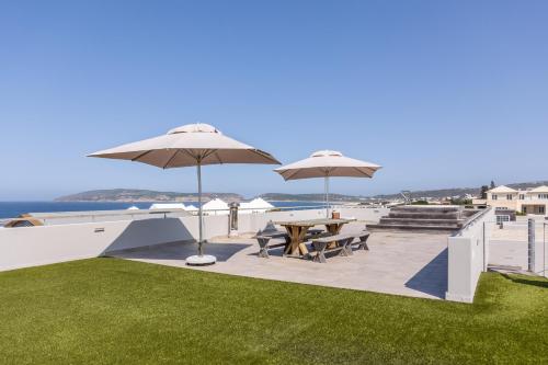 un patio con tavoli, ombrelloni e oceano di 41 on Beachy Head - Luxury Villa 100m from the beach a Plettenberg Bay