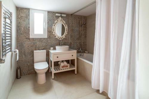 een badkamer met een wastafel, een toilet en een spiegel bij Floropounta in Trimiklini