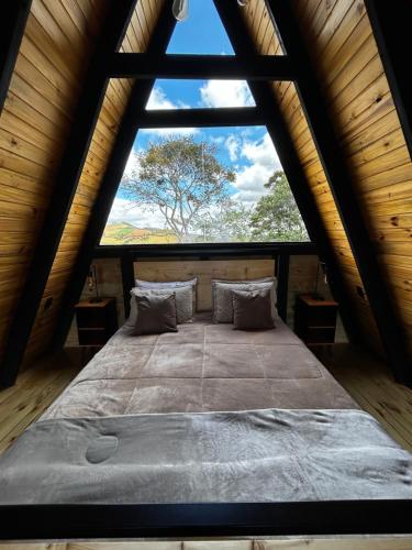 uma cama grande num quarto com uma janela grande em Cabana Jequitibá em Maria da Fé