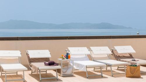 una fila de sillas y mesas blancas en un balcón en Hotel Il Telamonio, en Talamone