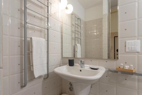 uma casa de banho branca com um lavatório e um espelho em La Perla Del Borgo Apartment em Florença