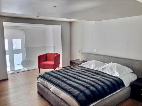 a bedroom with a large bed and a red chair at Loft Saint Thomas - Petite France in Strasbourg