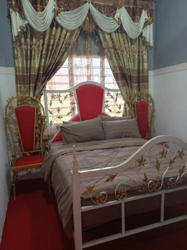a bedroom with a bed and two chairs in front of a window at Homestay ALHAQIM in Pontian Kecil