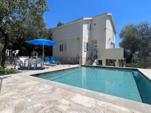 - une piscine avec un parasol en face d'une maison dans l'établissement Villa Olive Tree with Private Pool, à Luštica