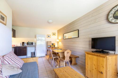 un salon avec une télévision et une table avec des chaises dans l'établissement A l'Orée des Cimes, aux Angles