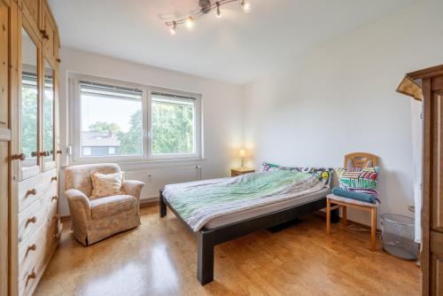 a bedroom with a bed and a chair and windows at Private Apartment in Hannover