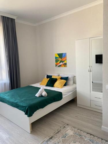 - une chambre dotée d'un grand lit avec des oreillers jaunes et bleus dans l'établissement ЖК Ару кала 3, à Taldykolʼ