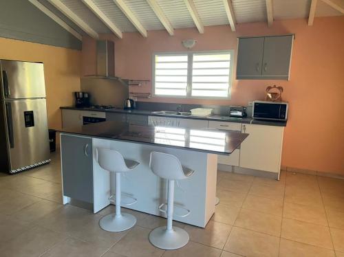a kitchen with a large counter with two stools at Ti Kaz en Nou' in Pointe-Noire