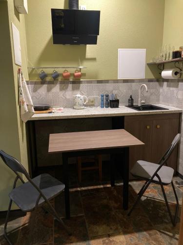 a kitchen with a sink and a table and two chairs at Pumpura apartamenti ***** in Talsi