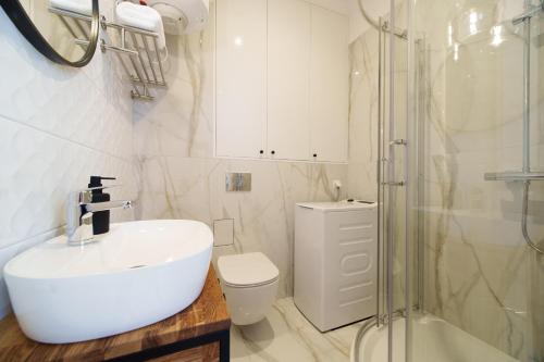 a white bathroom with a sink and a shower at Złota 8 Apartments in Białystok