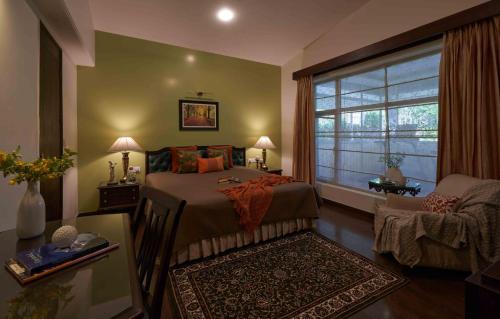Un dormitorio con una cama y una ventana y una silla. en Lohonostays Soni Estate, en Mussoorie