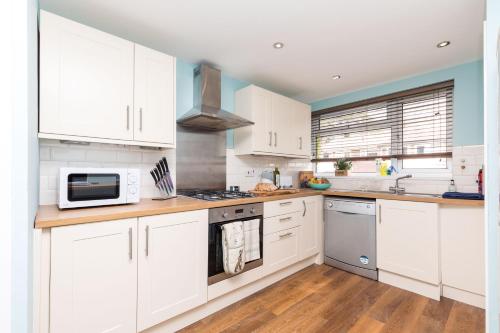 a kitchen with white cabinets and a microwave at Rivermead in Horsham