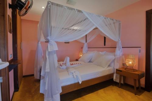 a bedroom with a canopy bed with white curtains at VILLA PANORAMA NOSY BE in Nosy Be