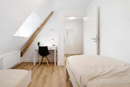 a white bedroom with two beds and a desk at Appartment Weiden in Gronau