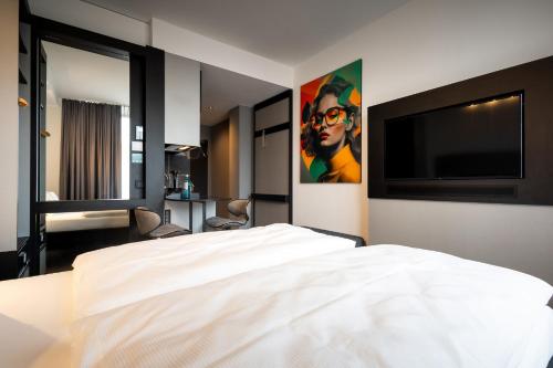 a bedroom with a white bed and a flat screen tv at GINN Apartment-Hotel Stuttgart-Esslingen in Esslingen