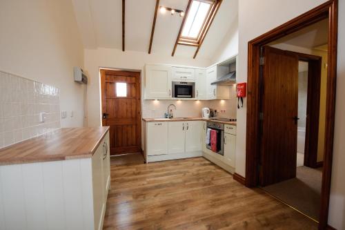 a kitchen with white cabinets and a wooden floor at Church Farm Lodge in Harrington